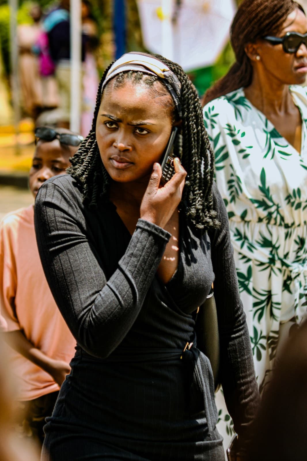 A woman with braids on her phone outdoors